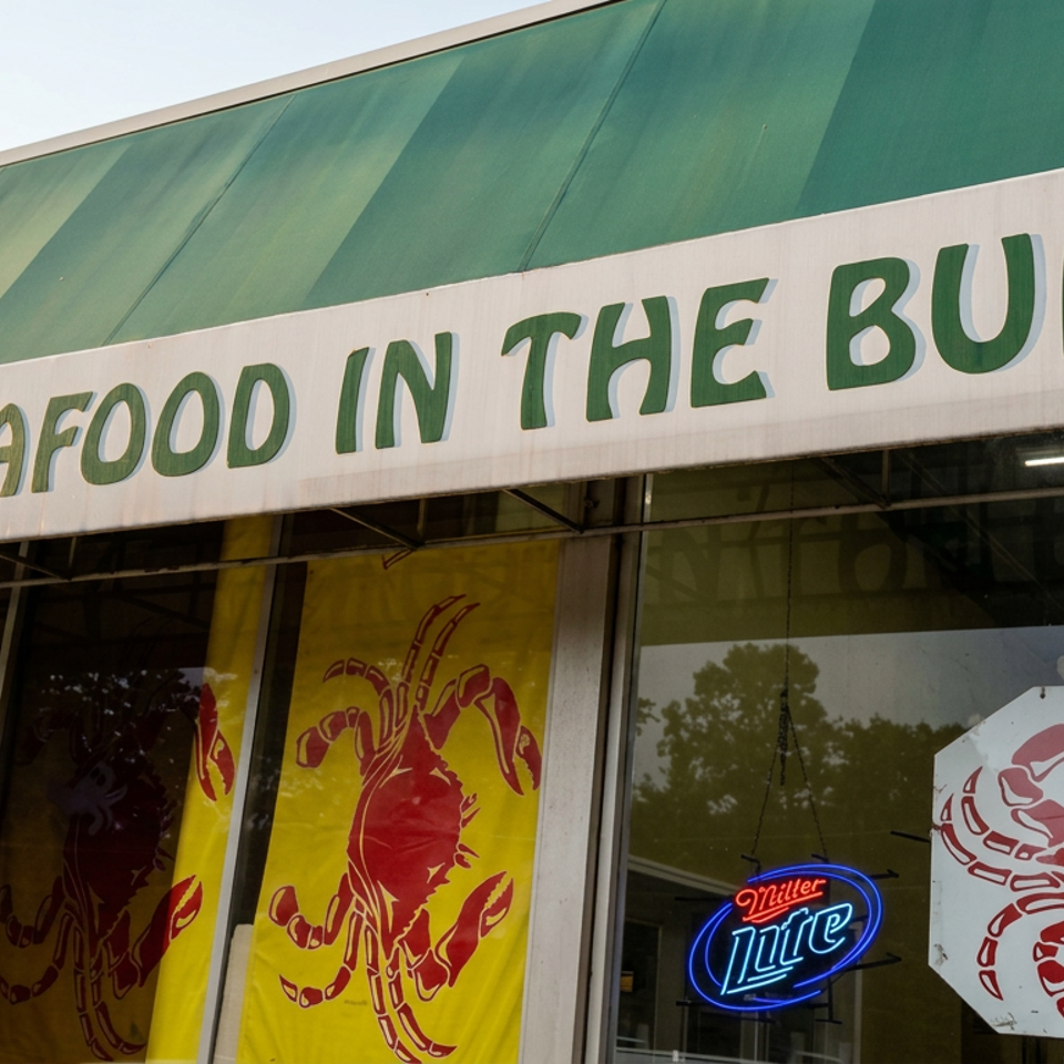 Seafood restaurant storefront with green awning, crab artwork, and a Miller Lite neon sign in the window.